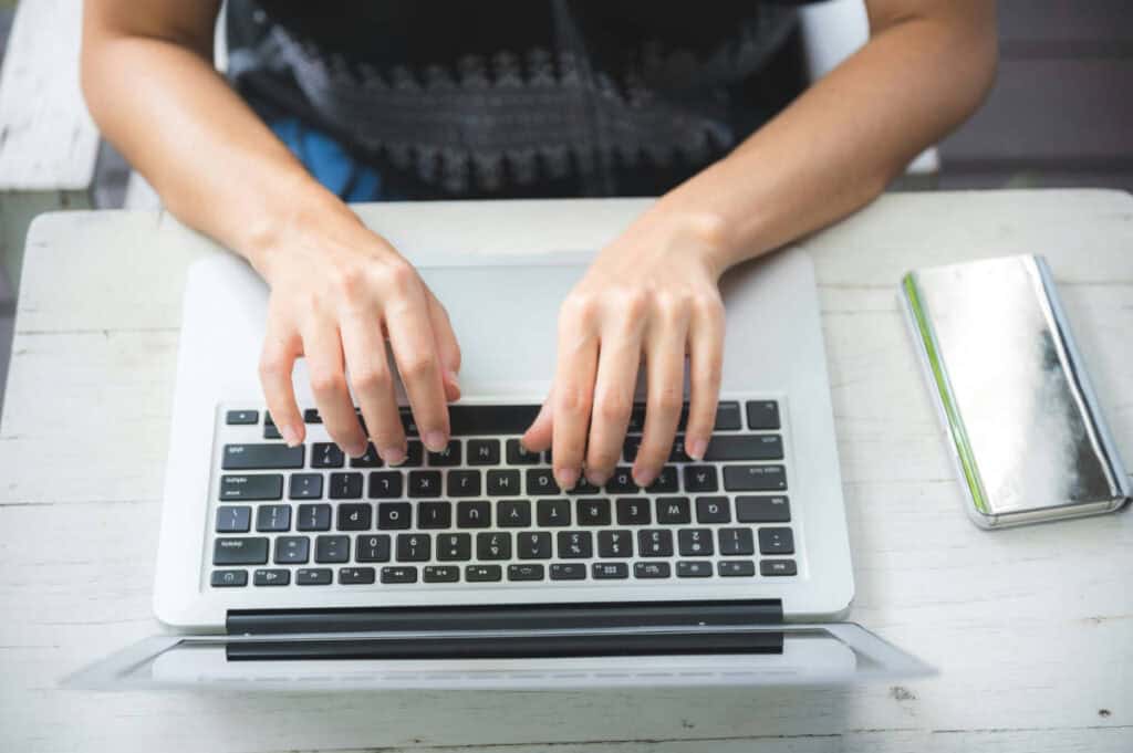 Person typing on a laptop keyboard for web design services.