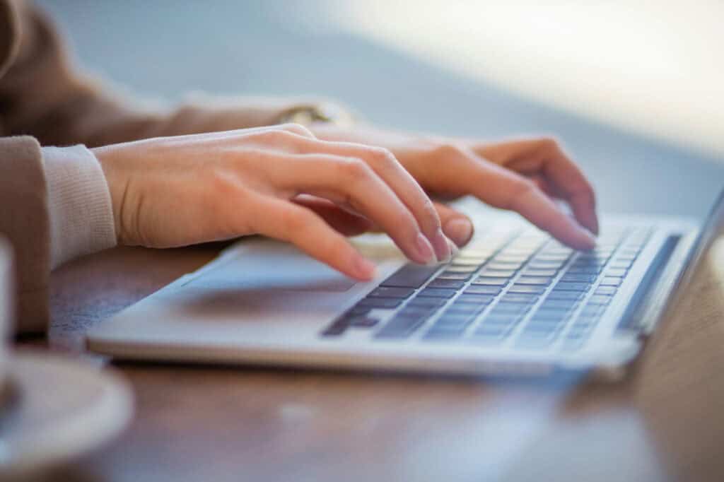 Person typing on a laptop keyboard for web design services.